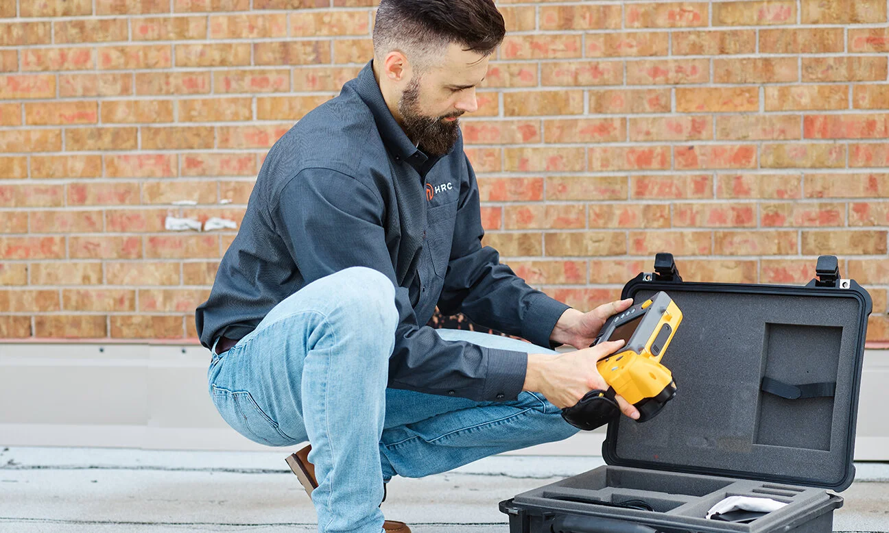 Heartland Roofing Consultants technician unpacking an infrared thermal camera on a rooftop